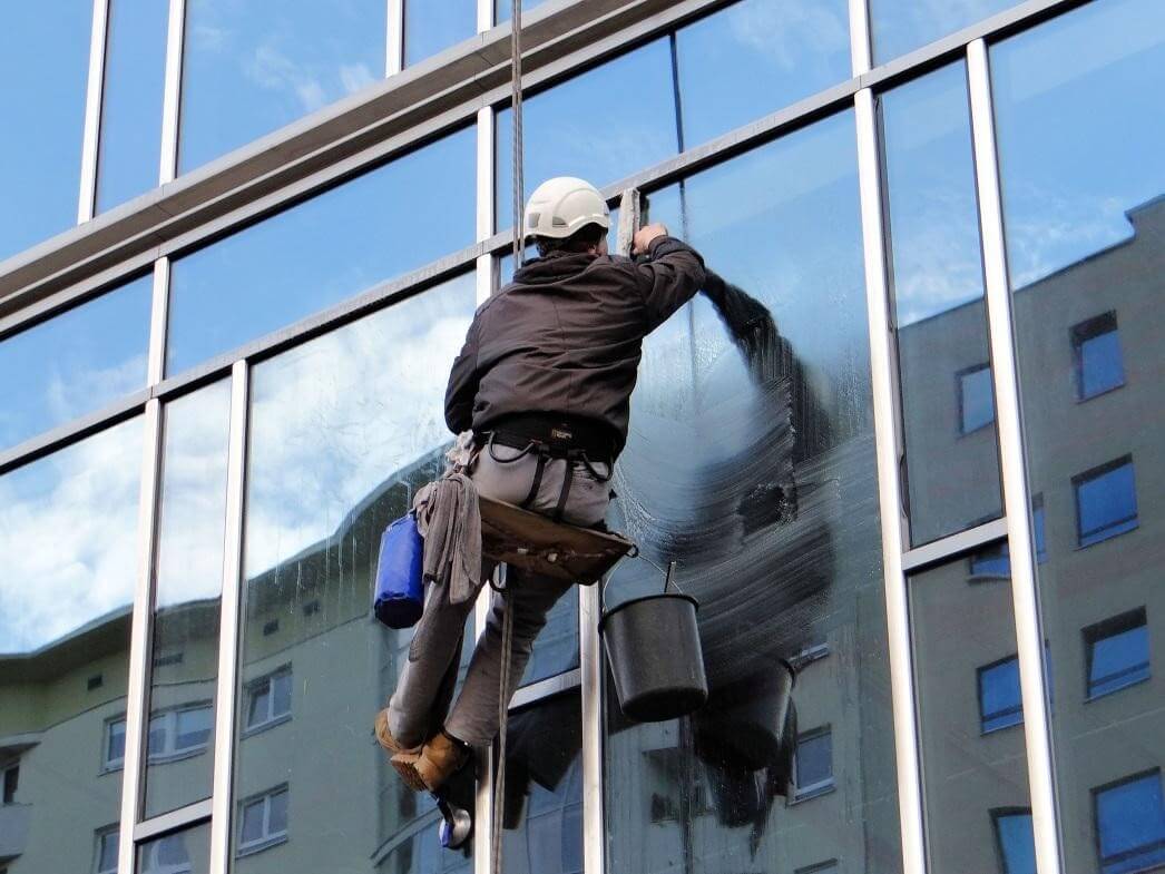 A technician from Window Ninjas Columbia cleaning the exterior windows of a high-rise office building.