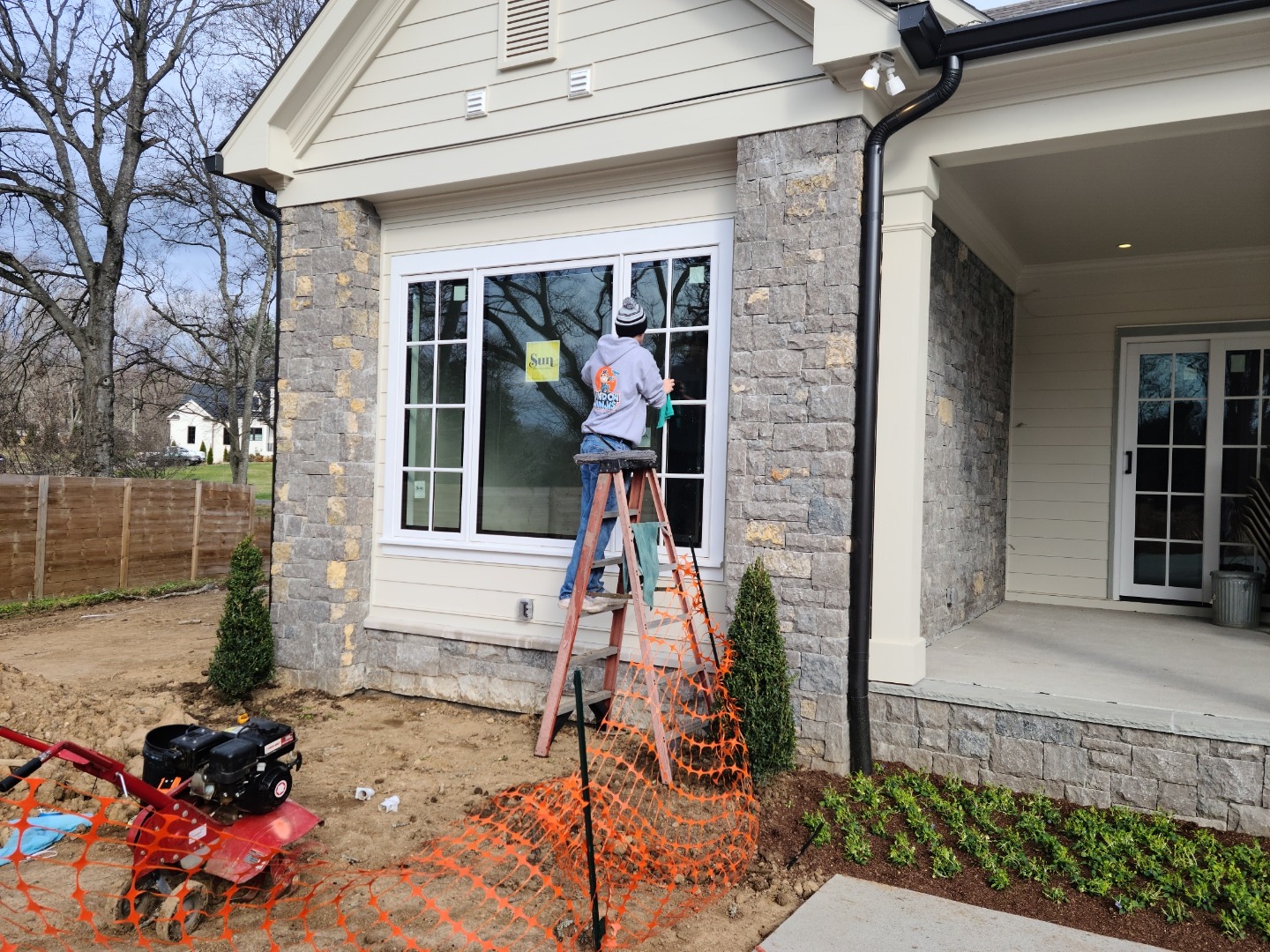 A technician from Window Ninjas outside a newly constructed home performing one of our Charlotte post construction window cleaning services.