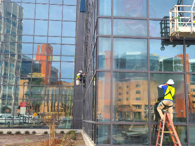 A Window Ninjas professional cleaning windows on the outside of a tall office building - contact us today to discuss our Columbia office window cleaning services!