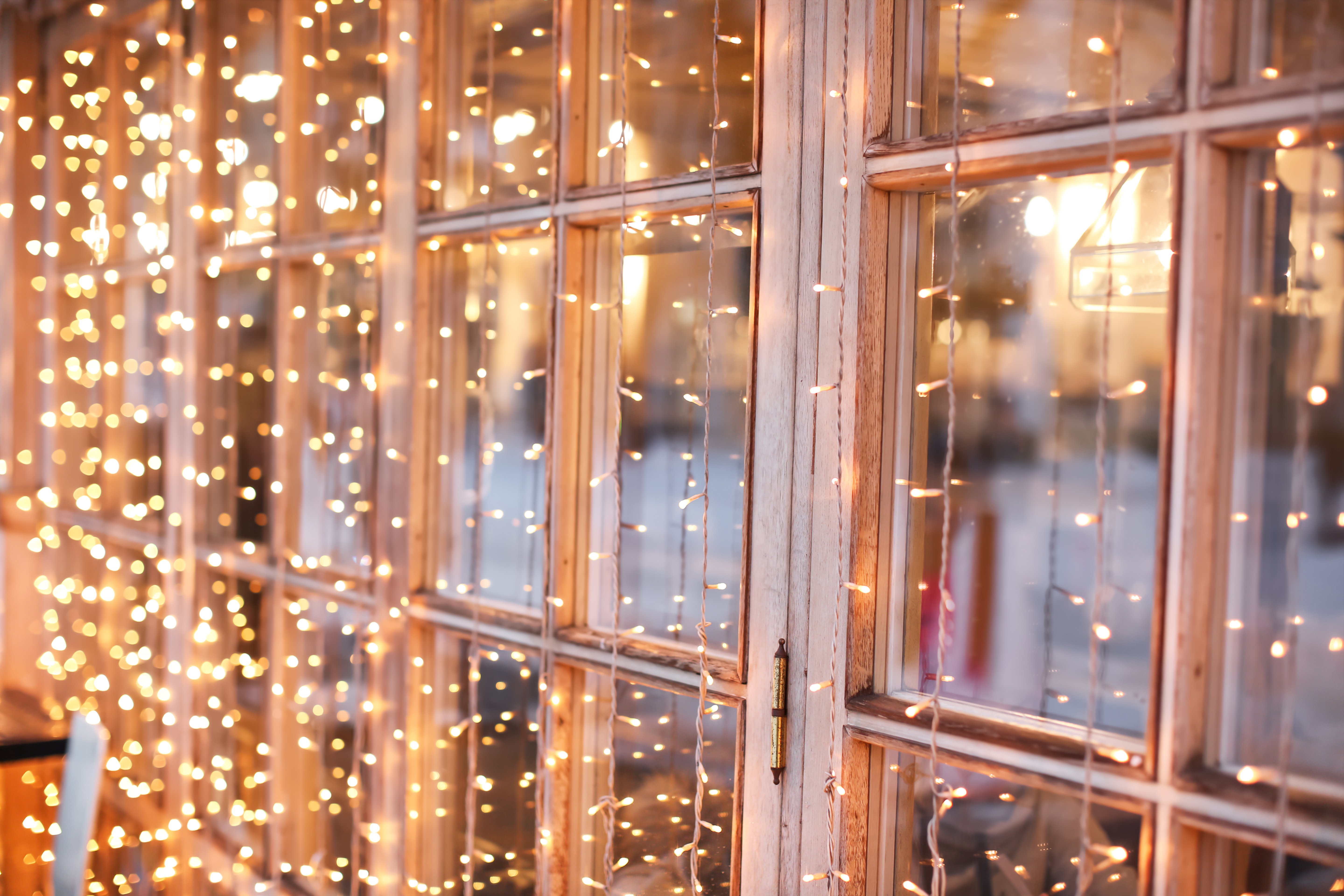 Holiday string lights hanging in front of a home's window - Contact Window Ninjas for residential Christmas light installation in Virginia Beach, VA.