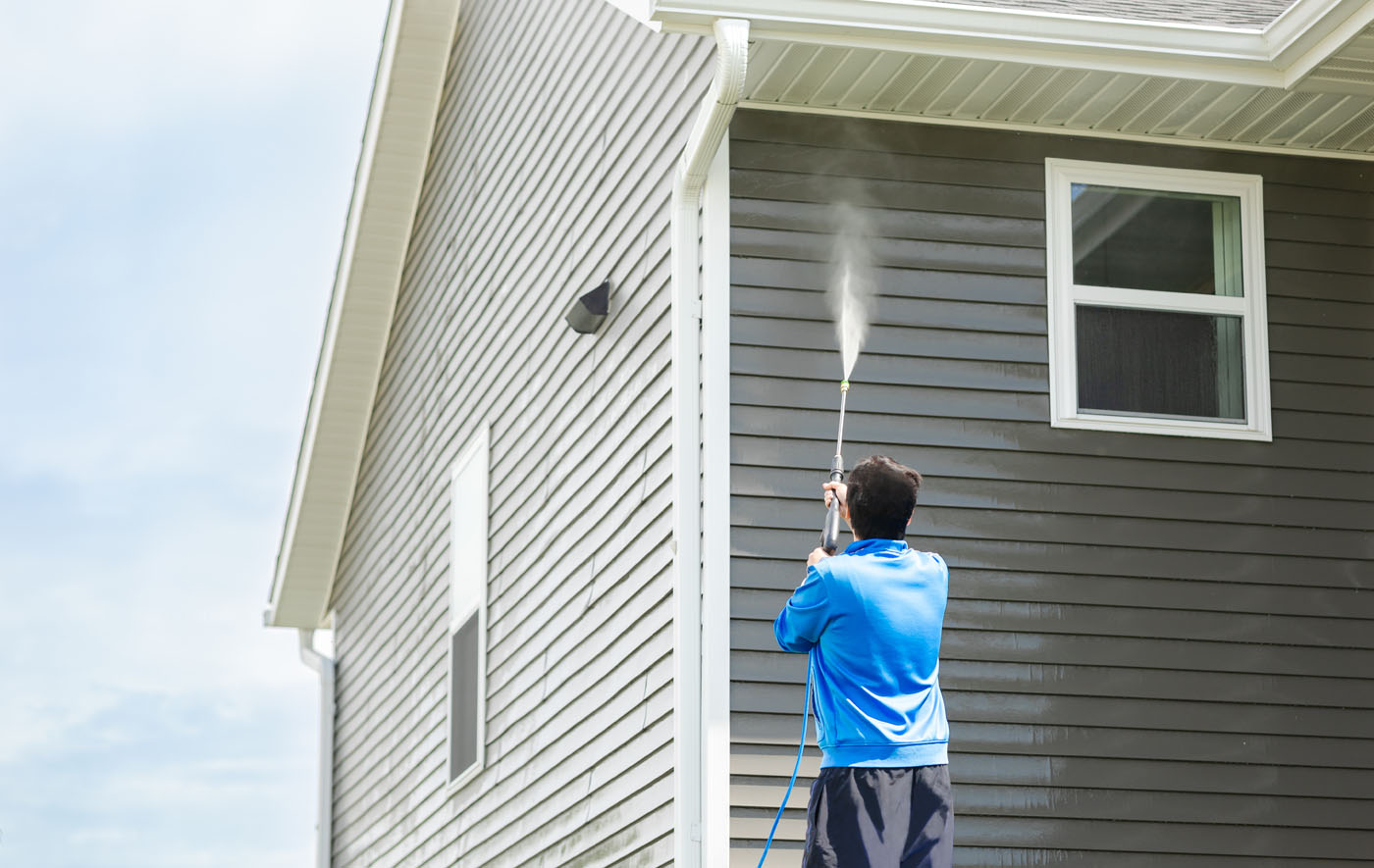 A person cleaning the exterior of their home with power washing - experience the best Nashville pressure washing services with Window Ninjas.