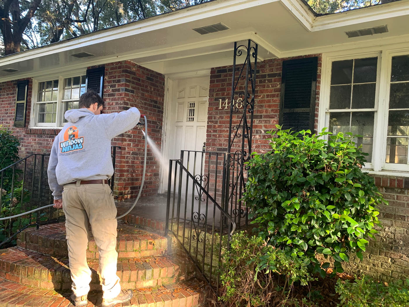 A Window Ninjas Nashville technician pressure washing a residential front porch.