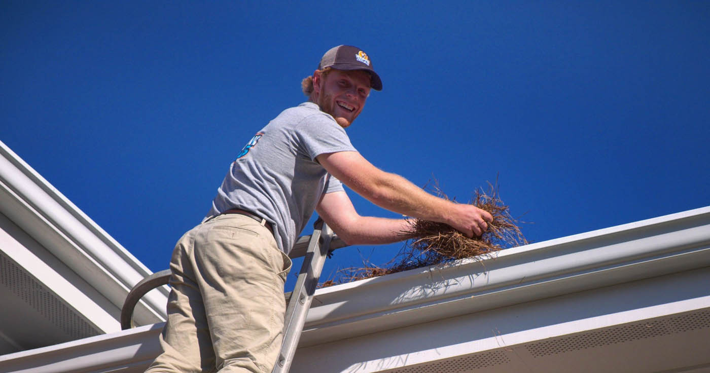 A Window Ninjas Richmond team member cleaning the gutters out for a residential home.