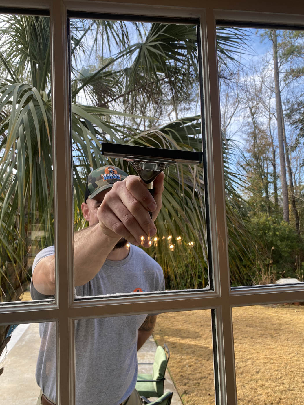 An expert Window Ninjas technician hand cleaning a home's window from the outside.