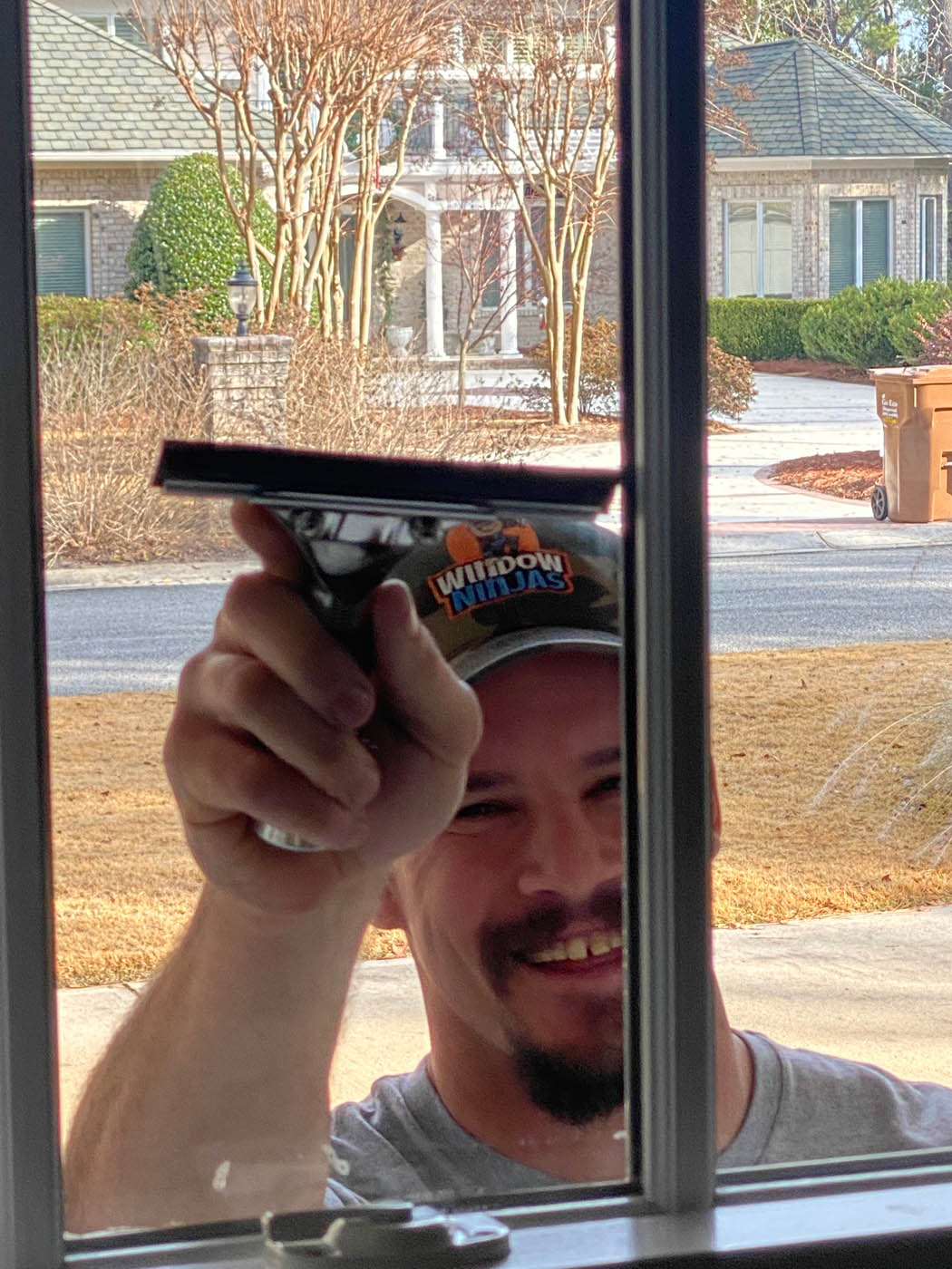 A Window Ninjas Greenville / Spartanburg window professional cleaning the outside of a window for a residential property.