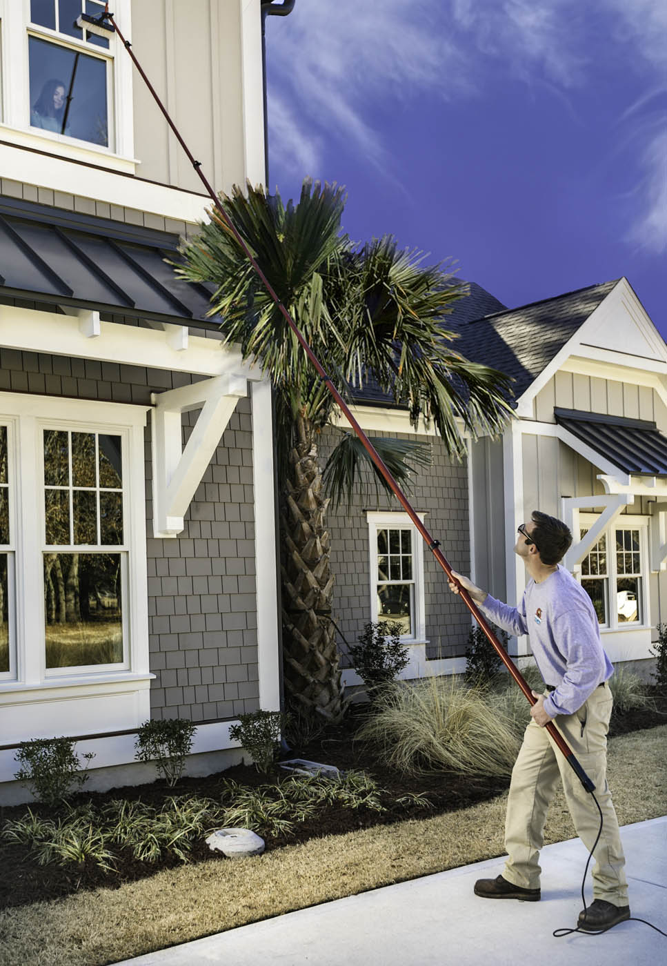 A Window Ninjas technician cleaning a high residential window.