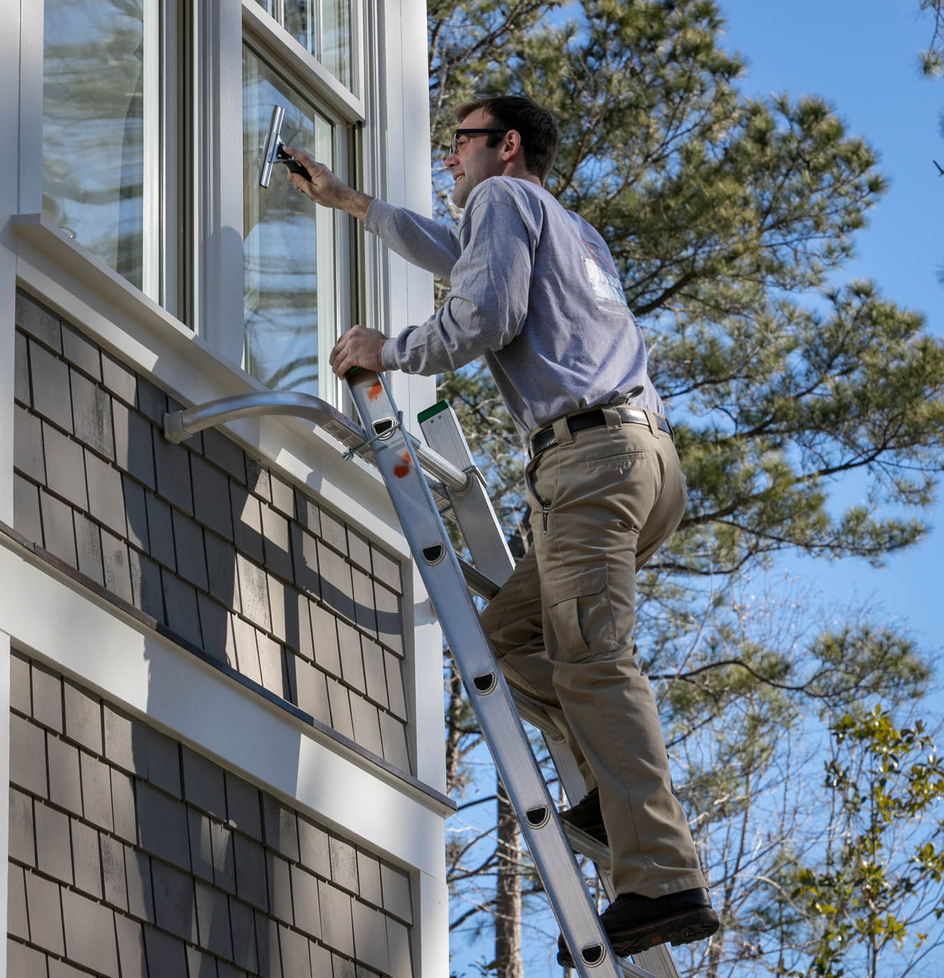 A Window Ninjas Greenville / Spartanburg window washing technician providing expert cleaning services for a residential home.