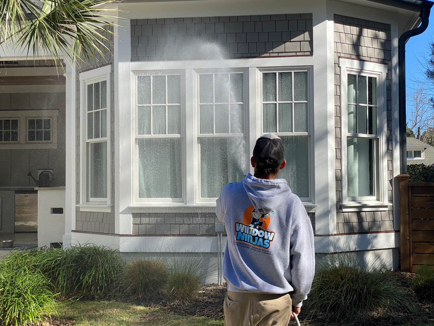 A Window Ninjas technician providing power washing window cleaning services for a residential home.