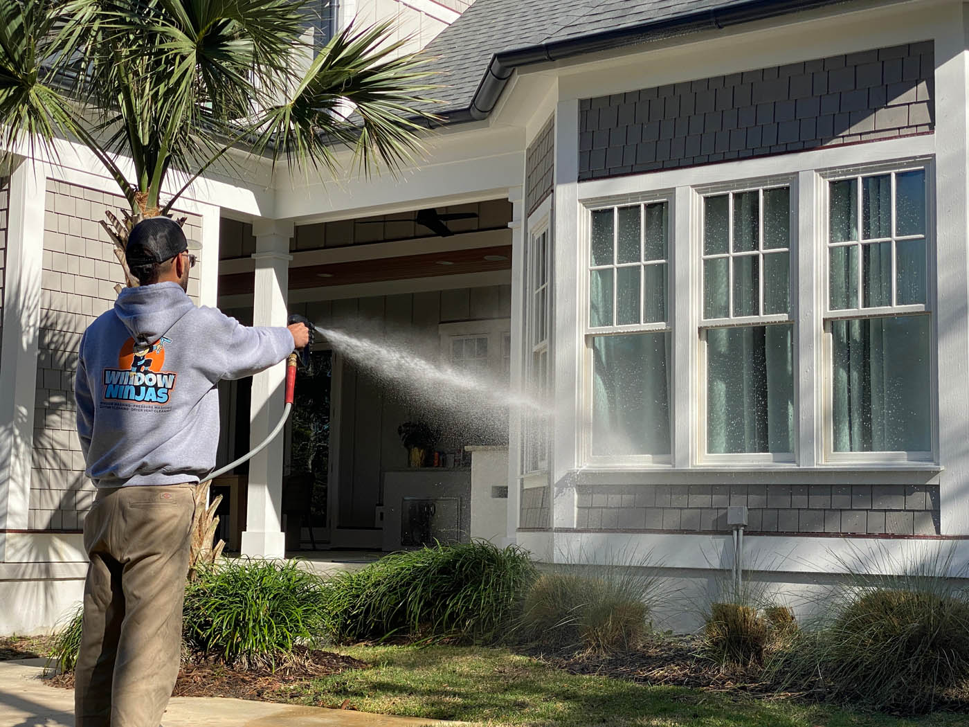 A Window Ninjas Nashville team member pressure washing the outside windows of a home.